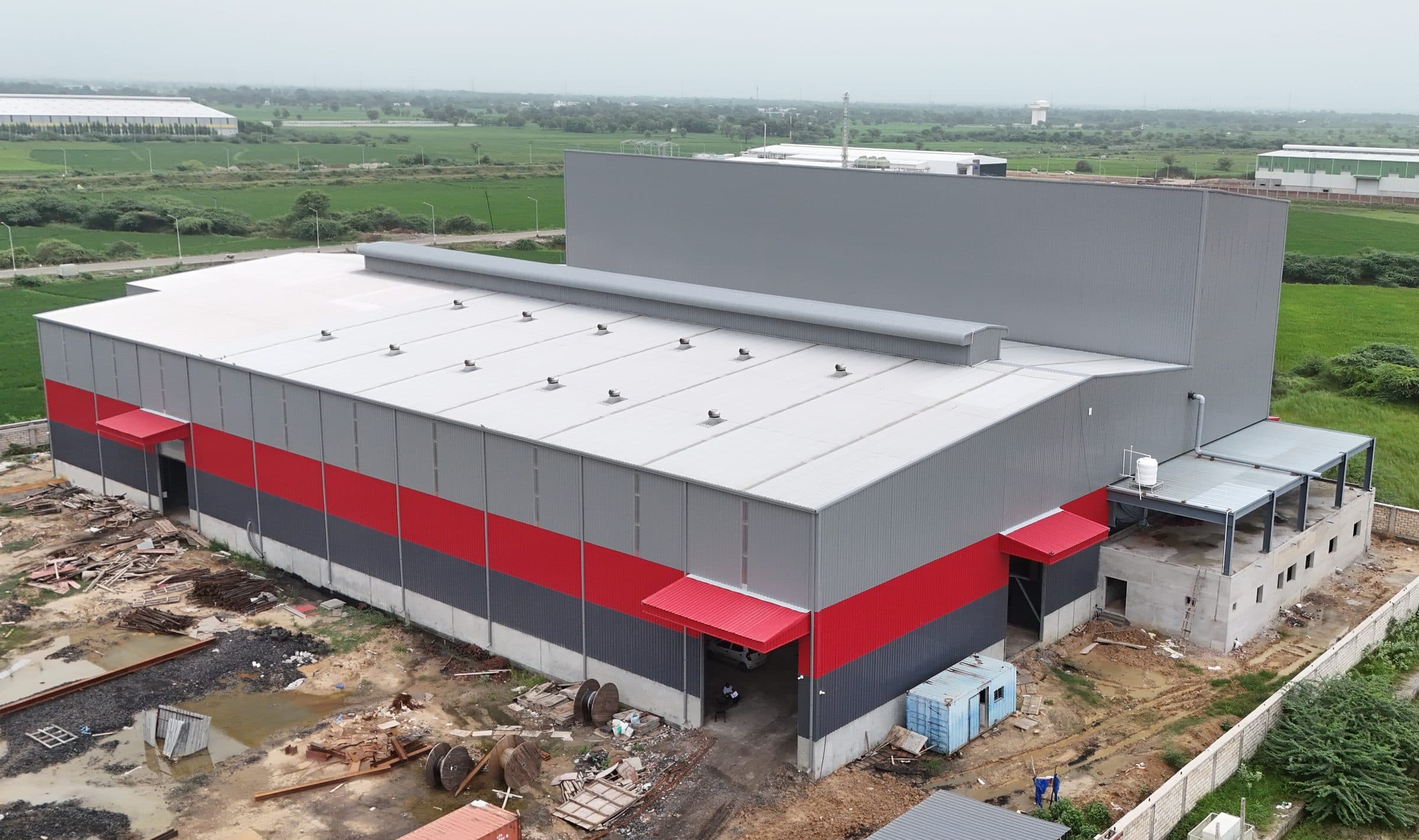Grey and red clad PEB factory, aerial view by AcuFabInfraStructure