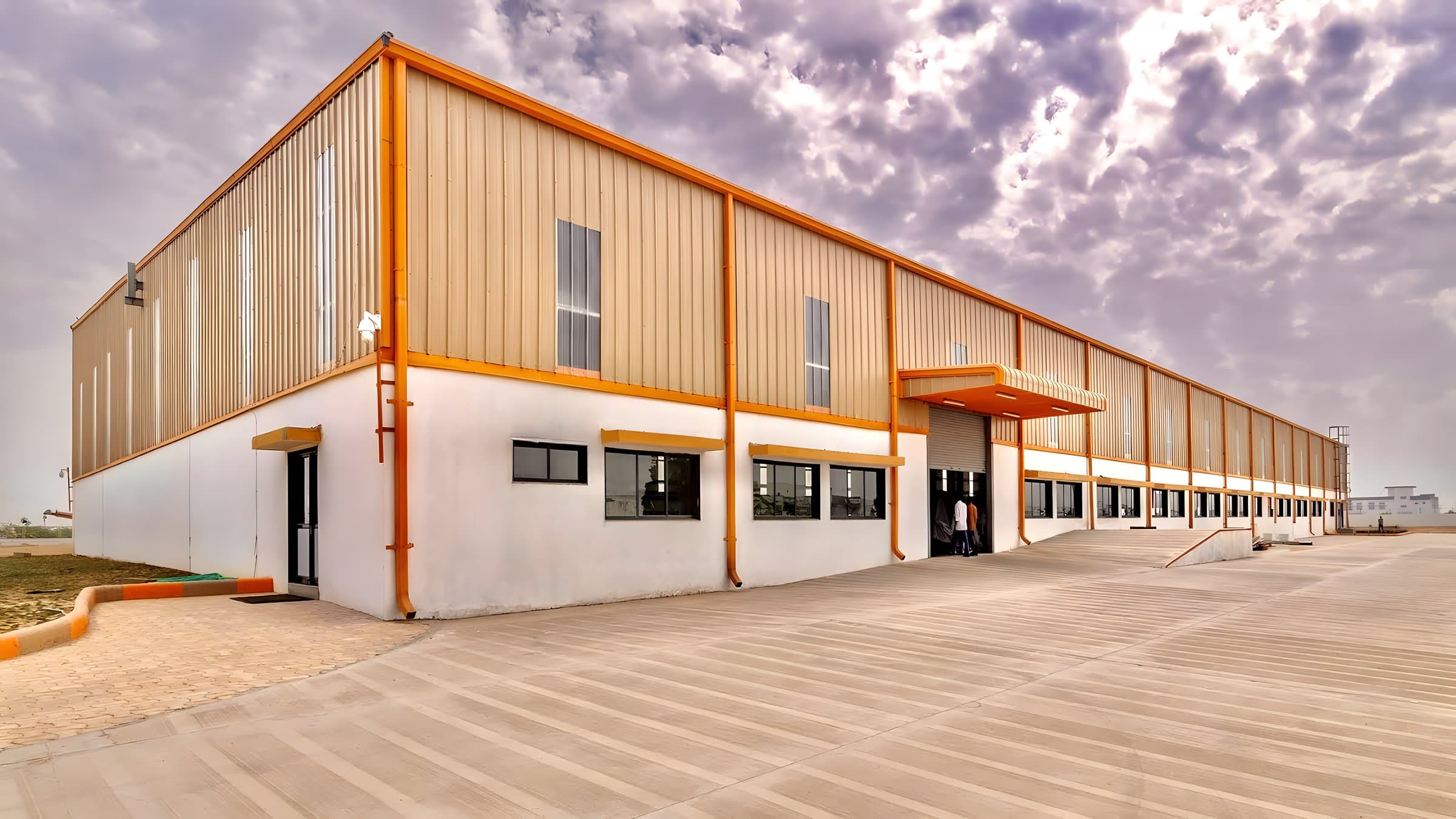 Beige-clad PEB building with attached office block by AcuFabInfraStructure