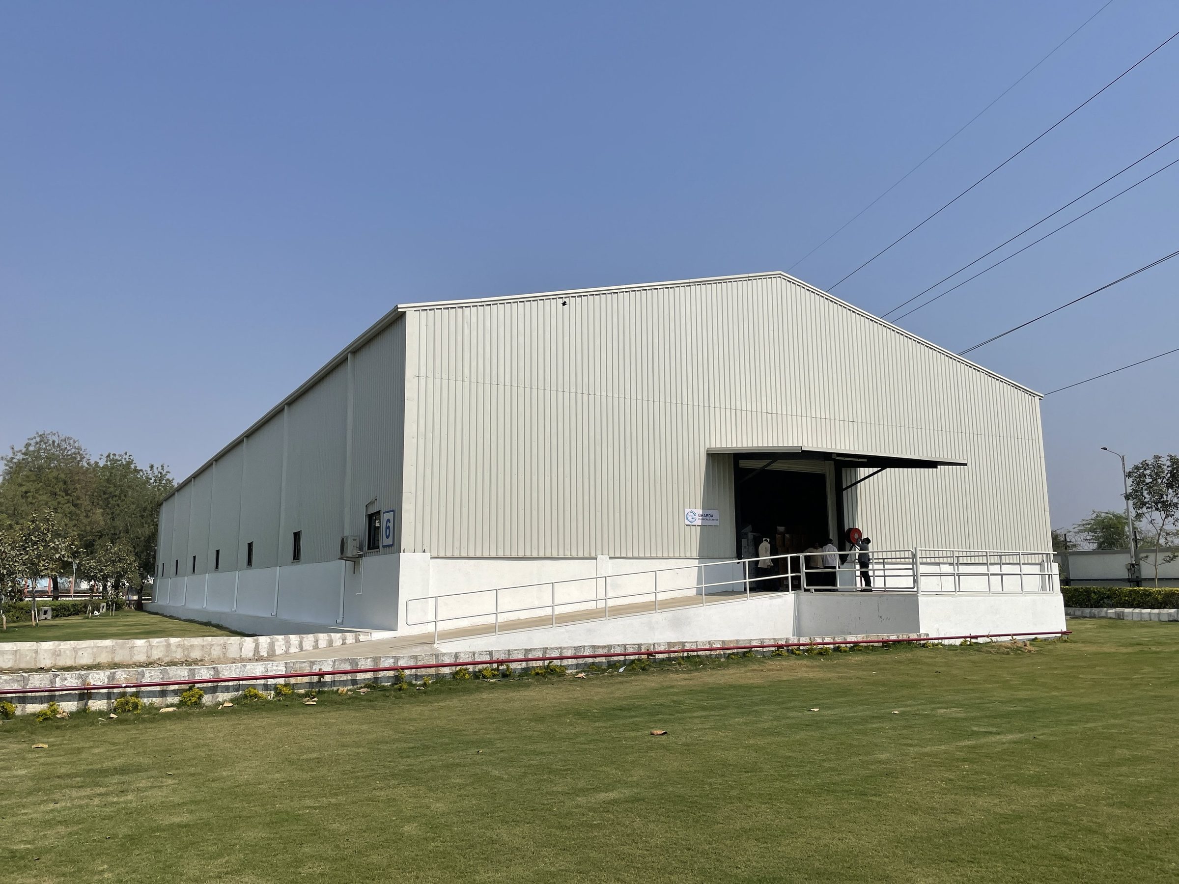 White PEB warehouse with loading ramp by AcuFabInfraStructure